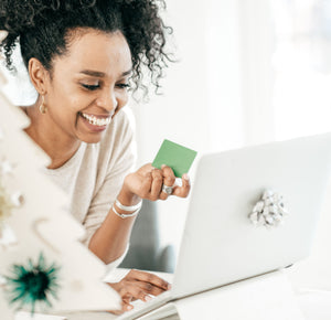 Woman holding gift card while browsing laptop